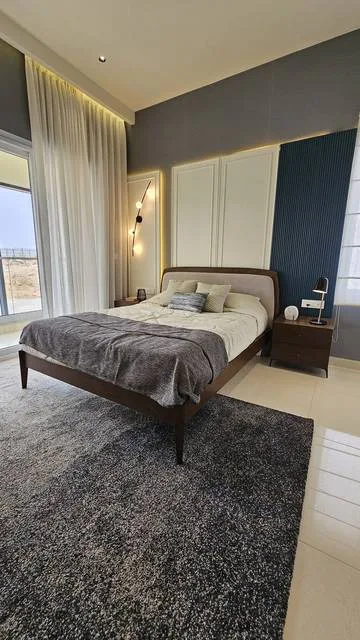 Bedroom with panelled bed-back wall and built-in wardrobe in a 3BHK by The Haus Projekt