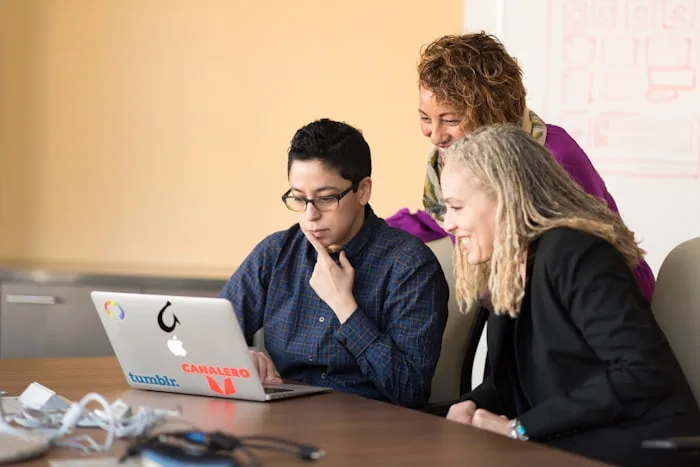 Three people reviewing drawings together at a laptop.